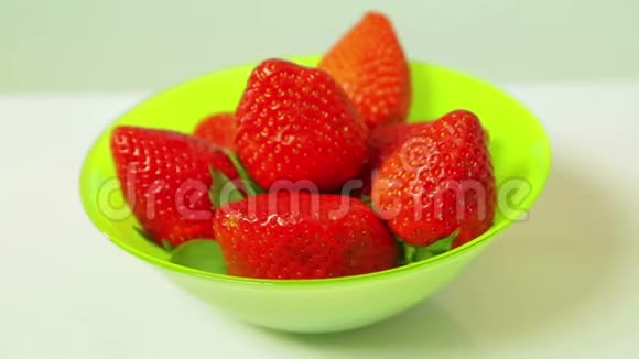 蓝色背景上绿色盘子里的红色新鲜草莓以圆圈旋转视频的预览图