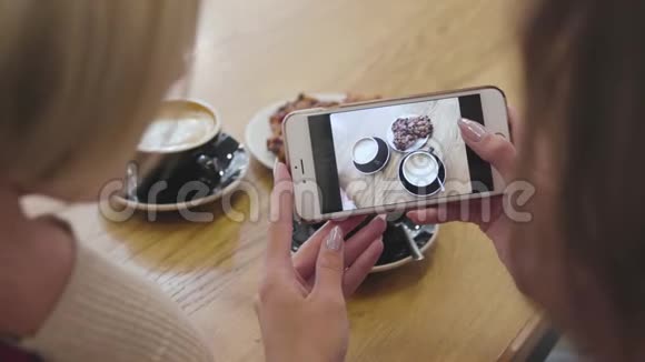 女子手拿食物拍照手机在咖啡厅特写视频的预览图