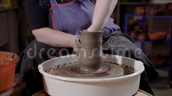 一个专业的女陶工在工作室塑造粘土的车轮特写镜头视频的预览图