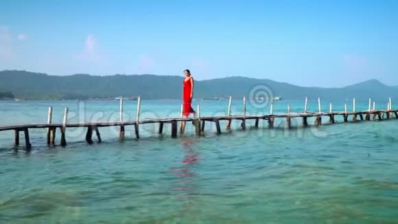 穿着红色长裙走在码头上的美女PhuQuoc岛那个女人走在皮尔西照相机开着灯视频的预览图