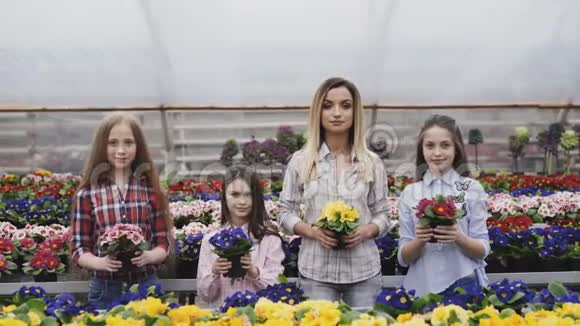 四个女孩微笑着把花盆和照相机同步伸展的肖像视频的预览图