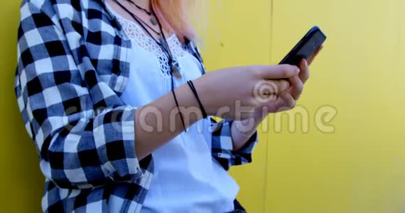 时尚女人用手机对着小巷里的黄墙视频的预览图