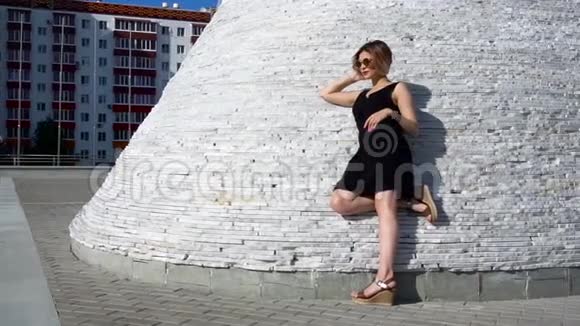 年轻时尚的年轻女性模特穿着黑色短裙和户外太阳镜在街上的肖像视频的预览图