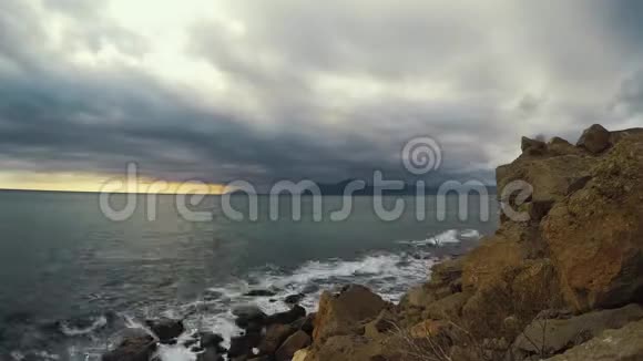 随着时间的推移海浪冲击着石岸阴云密布的天空在岩石和斗篷面前移动视频的预览图