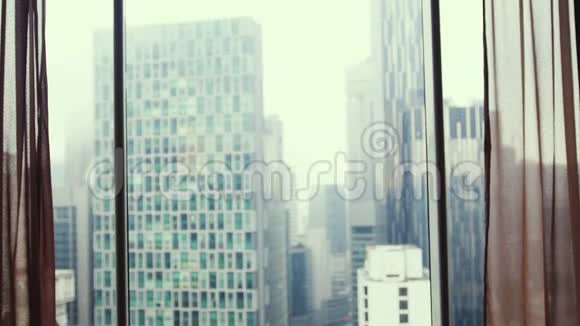 布鲁内特女士走到窗前站在大窗户旁边望着城市建筑上的公寓3840x2160视频的预览图