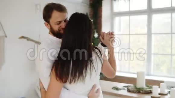 在圣诞树旁时髦的公寓里一对漂亮的年轻情侣在爱情中欢舞视频的预览图