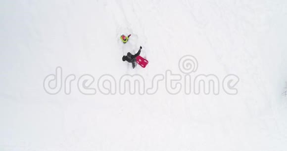 冬天的头顶俯视着父亲拉着红色的雪橇和孩子一起飞升爸爸儿子或女儿瑞雪视频的预览图