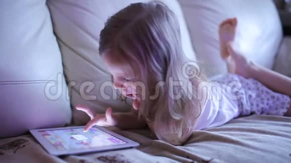 小可爱的女孩躺在沙发上玩平板电脑视频的预览图