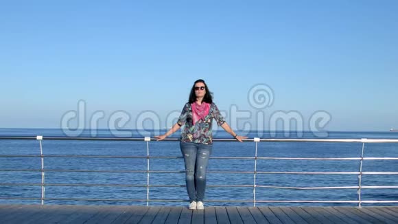 漂亮的女人站在海边码头4K夏时视频的预览图