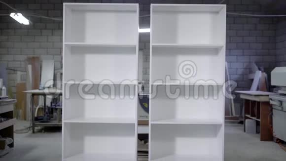 两个有架子的白色成品橱柜站在木工车间里垂直全景视频的预览图