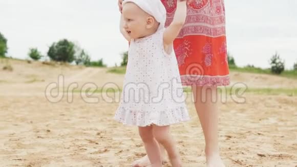 快乐的宝宝在沙滩上和妈妈一起迈出第一步视频的预览图