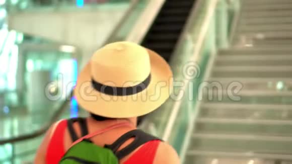 那个穿着红色连衣裙和帽子的女人在机场上楼机场戴着帽子和背包的女人走了视频的预览图
