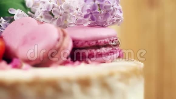 在手工制作的蛋糕上用马卡龙草莓切片和紫丁香四K慢莫内景装饰视频的预览图