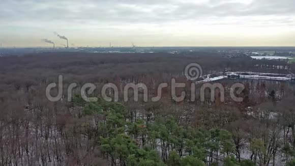 鸟瞰冬季森林与工业背景的杜伊斯堡城市与烟囱的背景视频的预览图