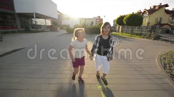 男孩和女孩牵着手在沥青上一起跑他们玩得很开心视频的预览图