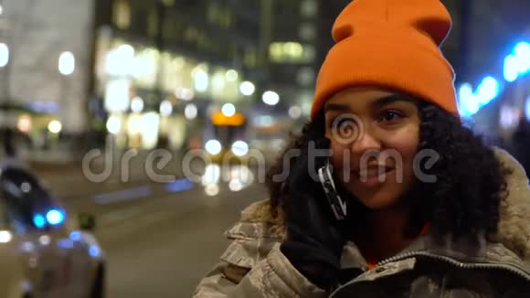 美丽的混血女青少年女孩女孩女孩晚上用手机与亚历山大广场车站的电车交谈视频的预览图