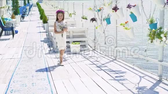 快乐的小女孩带着一束鲜花走到海湾酒吧的镜头前4K视频的预览图