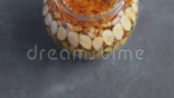 黑桌上有蜂蜜坚果的罐子特写俯视图视频的预览图