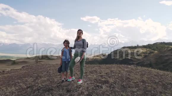 一个带着孩子的女人欣赏山景带背包的游客家庭妈妈和小女儿视频的预览图