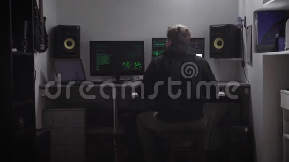 一个穿黑色衣服的男人坐在桌子旁的后景网络间谍从他房间侵入电脑数据库视频的预览图
