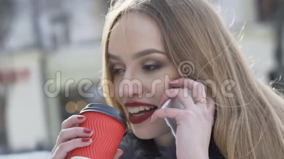 可爱的女孩在打电话在冬季大街喝咖啡视频的预览图