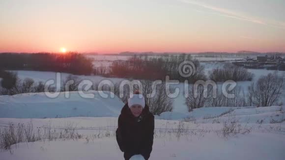 女孩走在冬天的树林里扔雪微笑笑在新鲜空气中游走日落视频的预览图