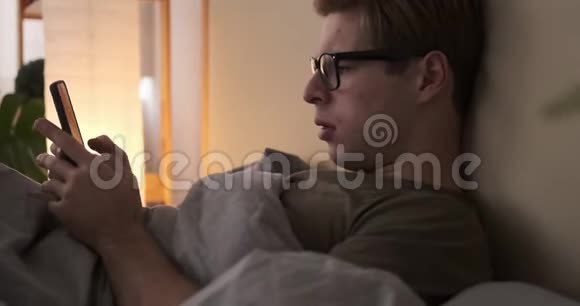 年轻人在床上用手机视频的预览图
