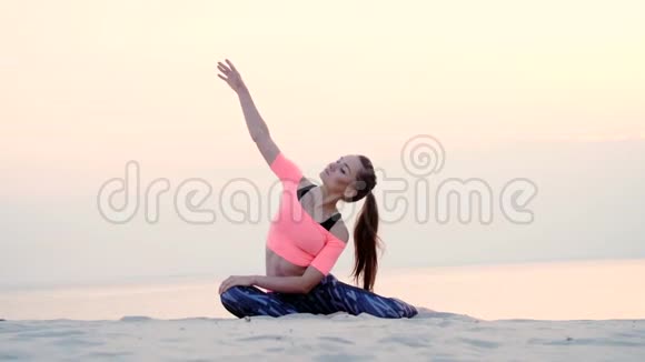 女人坐在海边放松瑜伽姿势日出的时候放松肌肉心灵获得和谐视频的预览图