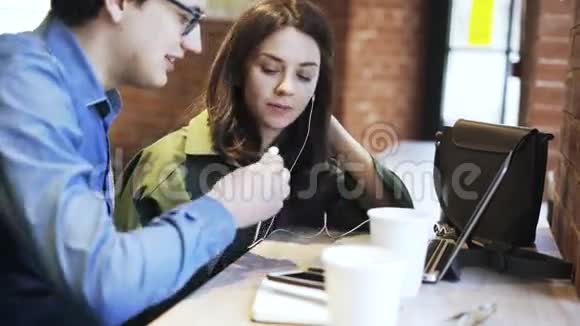 一对千年夫妇在咖啡馆里一起使用耳机的侧景视频的预览图