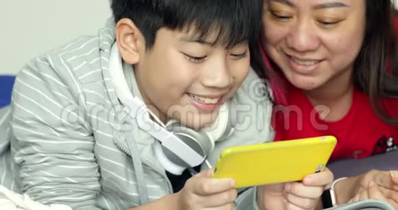 快乐的年轻母子在手机上观看然后他们微笑着透过电话视频的预览图