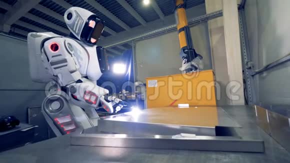 仿人机器人焊工在工厂地板上焊接金属板视频的预览图
