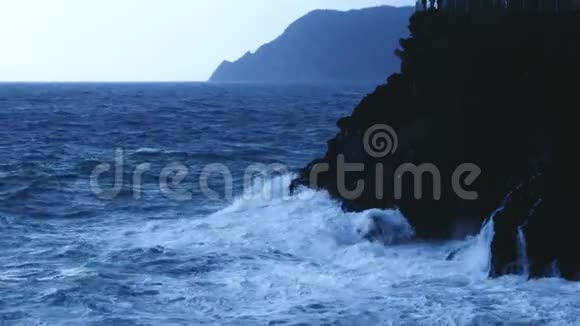 蓝色的海水波浪撞击岩石悬崖形成泡沫暴风雨天气视频的预览图