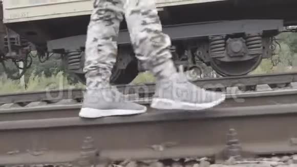 穿着运动鞋的腿和穿着防护裤的人在铁轨上行走视频的预览图