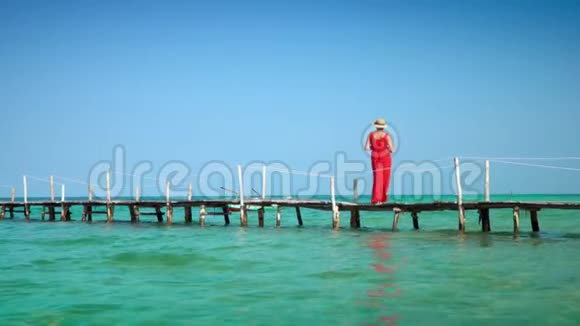 穿着红色长裙走在码头上的美女PhuQuoc岛那个女人花了一笔钱在皮尔西的照相机上视频的预览图