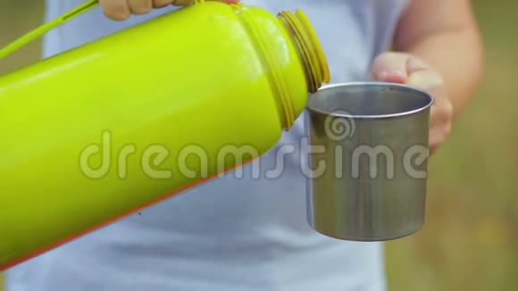 女人把热水瓶里的茶倒进杯子里视频的预览图