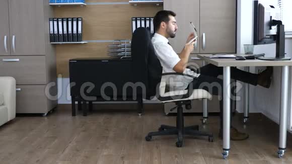 办公室里的年轻商务人士一边在笔记本上做笔记一边在椅子上滑来滑去视频的预览图