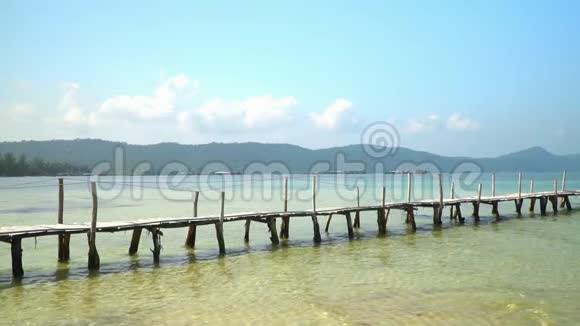 戴草帽的女人在绿松石水上的码头上海滩上美丽的风景白色热带沙视频的预览图