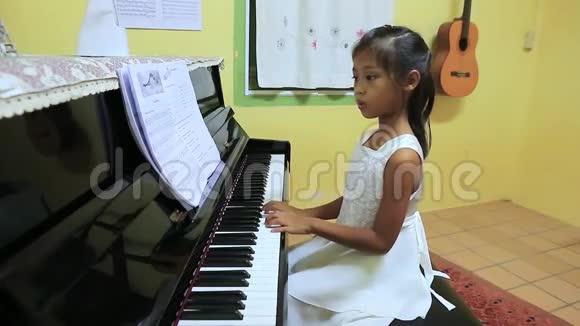 一个穿着白裙子的可爱的亚洲女孩弹钢琴视频的预览图