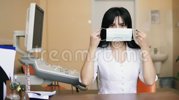 一位女医生在镜头下看着并戴上一个保护性手术面罩的肖像她正坐在视频的预览图
