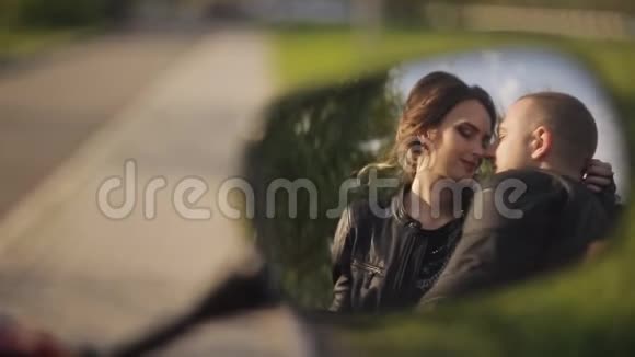 在高速公路的背景下穿着皮夹克的约会男女坐在摩托车上接吻反思视频的预览图