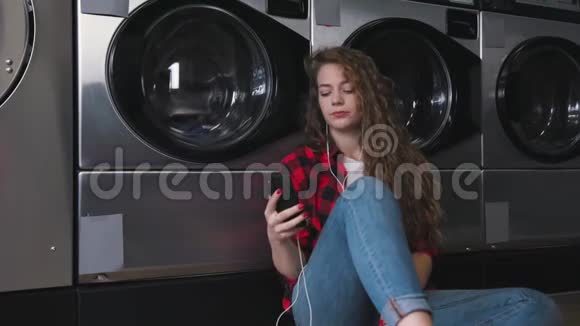 年轻漂亮的女人红色的卷发穿着红色的酒石衬衫听音乐打电话洗衣店跳舞视频的预览图