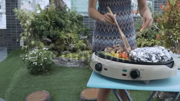 女孩把肉和蔬菜放在植物的烧烤上视频的预览图