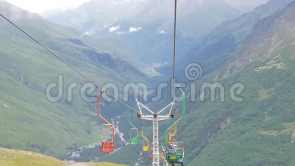 夏天在一个空的滑雪场坐电梯参观山谷和冰川的游客视频的预览图