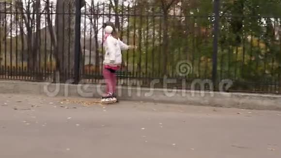 女孩骑着旱冰车在秋天的公园里视频的预览图