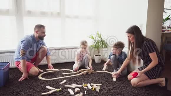 母亲和父亲帮助他们的孩子建造玩具铁路视频的预览图