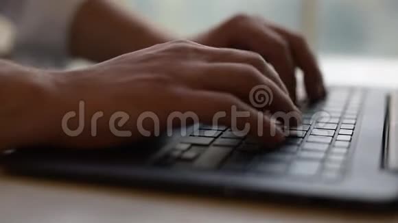 特写镜头男人用手在笔记本电脑键盘上打字视频的预览图