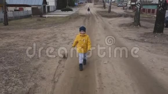 穿着黄色夹克和帽子的男孩走在街上视频的预览图