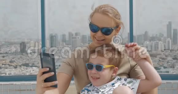 妈妈和孩子在酒店屋顶上用手机自拍以色列特拉维夫视频的预览图