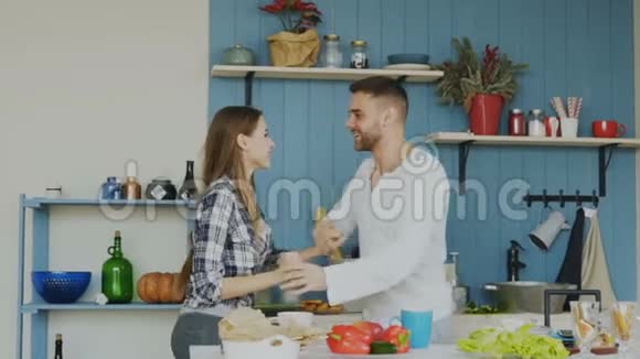 一对快乐而有魅力的年轻情侣在家里的厨房里一起跳拉丁舞视频的预览图
