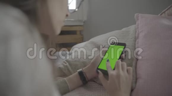 绿色屏幕用带有色度键的手机拍摄长黑发的年轻白种人女性的肩部镜头视频的预览图
